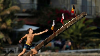 A child tries to grab a flag on the “gostra”, a pole covered in grease, during the religious feast of St Julian, patron of the town of St Julian’s, outside Valletta, Malta. In the traditional “gostra”, a game stretching back to the Middle Ages, young men, women and children have to make their way to the top and try to uproot one of the flags to win prizes. Darrin Zammit Lupi / Reuters