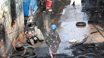 A woman with a helmet walks among debris at a burnt tyre market after clashes in New Delhi, India. EPA