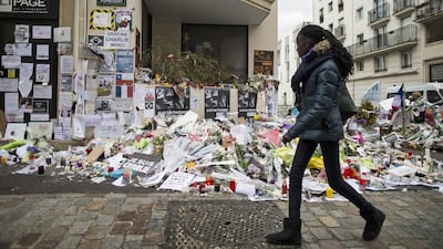 A girl walks past the hundreds of flowers near the Charlie Hebdo offices in Paris. Photo: Ian Langsdon / EPA
