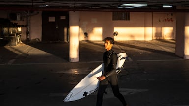 A man carrying a surfboard exits an underground parking used as a bomb shelter after an alert in Tel Aviv. AFP
