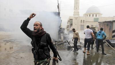 A Free Syrian Army fighter walks away as residents try to put out a fire after what activists said was shelling from forces loyal to president Bashar Al Assad on a fuel vendor in Aleppo. Molhem Barakat / Reuters