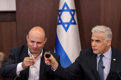 Naftali Bennett, left, and Yair Lapid share a toast during a cabinet meeting in Jerusalem, in 2022. AFP