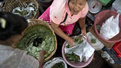 A retail seller, left, buys betel leaves from a wholesale vender at a market in suburban Yangon, Myanmar. The bright green betel leaves, as large as an adult palm, normally cost $1.80 to $2.50 per kilogram. Gemunu Amarasinghe / AP
