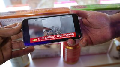 Turkish sweet vendors at Dubai Waterfront Market watch earthquake updates on a phone. Victor Besa / The National