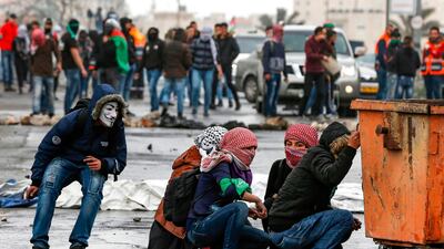 Palestinian girls with their faces covered with traditional chequered keffiyehs hide behind a bin during clashes with Israeli forces following a demonstration marking "Land Day". AFP