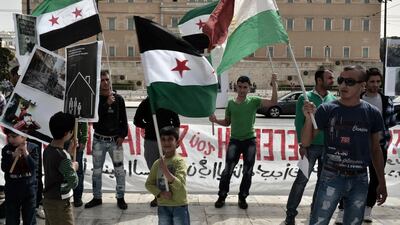 Syrian and Greek protesters hold placards and flags in front of the parliament building in central Athens on April 6, 2013, in solidarity with the refugees who have fled the conflict in Syria and demanded asylum from the Greek government and the European Union. Syrian refugees remain stranded in Greece and have experienced hostility and inaction. Louisa Gouliamaki / AFP