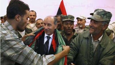 Libyan Transitional National Council chairman Mustafa Abdul Jalil, center, receives a Libyan flag amid Libyan veterans after a press conference in Benghazi Monday. Libya's transitional leader has ordered an investigation into the death of Muammar Qaddafii after the US and other international powers pressed for the probe.