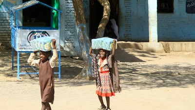 Displaced Sudanese children carry packs of humanitarian aid Gadaref city in war-torn Sudan on March 6, 2024. AFP