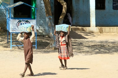 Displaced Sudanese children carry packs of humanitarian aid at a school where their families have taken refuge near Gadaref in eastern Sudan. AFP