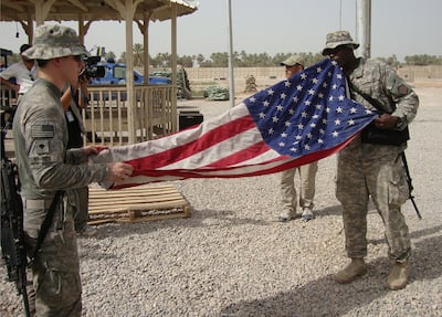 American soldiers fold their national flag while preparing to leave a military base in Hila, south of Baghdad. EPA