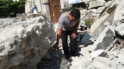 A church worker inspects a bell from the 18th century St. Catherine of Alexandria after its bell tower was destroyed.A FP