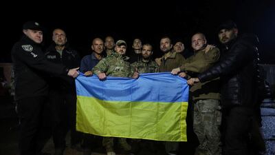 Some of the Ukrainian prisoners of war pose for a picture with their country's flag. Reuters