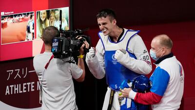 Vladislav Larin of the Russian Olympic Committee celebrates with coach as his family is watching via a video link after winning a gold medal for taekwondo men's 80kg match.