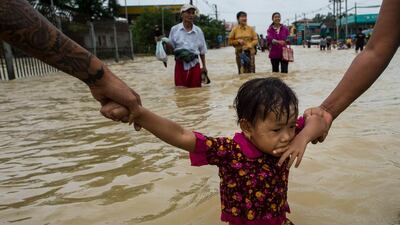 Residents hold onto a child as they walk through floodwaters in the Bago region, Myanmar. Ye Aung Thu/AFP