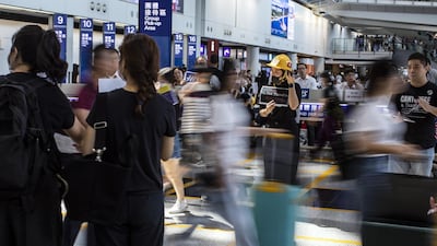 Travellers walk past demonstrators at Hong Kong International Airport. Bloomberg