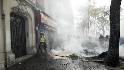 A Yellow Vest protester walks by a building through smoke during a demonstration of the French trade unions members and the Gilets Jaunes movement marking Labor Day in Paris. EPA