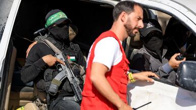 Hamas militants escort Red Cross members searching for hostage remains near the 'yellow line' in Gaza city. Reuters
