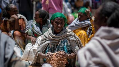 An Ethiopian woman scoops up grains of wheat distributed by an aid organisation in Tigray, where millions rely on assistance due to the regional conflict. AP