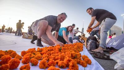 Thousands of volunteers laying out fresh flowers in an attempt to create the world's largest fresh flower carpet with the theme of Tolerance to highlight the UAE as a global capital for tolerance at Dubai Festival City. Leslie Pableo for The National