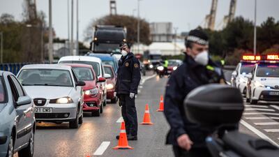 Police officers wear protective face masks as they direct traffic through a checkpoint in Barcelona, Spain. Bloomberg