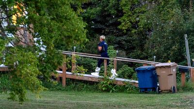 A coroner enters a house at the scene of a stabbing in Weldon, Saskatchewan. AP