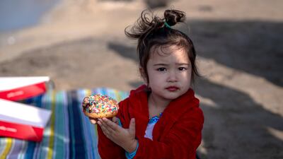 A young bystander enjoys a breakfast doughnut.