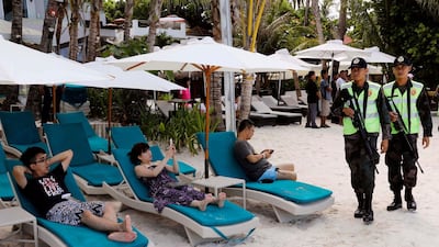 Policemen walk past tourists, one day before the temporary closure of the holiday island Boracay, in the Philippines on April 25, 2018. Erik De Castro / Reuters