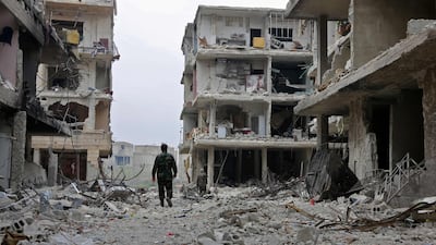 Syrian government soldiers walk down a street past destroyed buildings in the town of Hazzeh in Eastern Ghouta, on the outskirts of the Syrian capital Damascus, on March 28, 2018. AFP