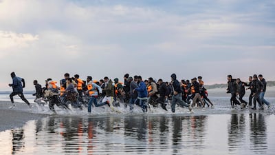 Migrants run to board a smuggler's boat in an attempt to cross the English Channel off the beach of Gravelines, northern France in August. AFP