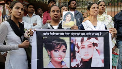 Mourners hold Sridevi posters as they wait outside her residence to pay their last respects. Rafiq Maqbool / AP Photo