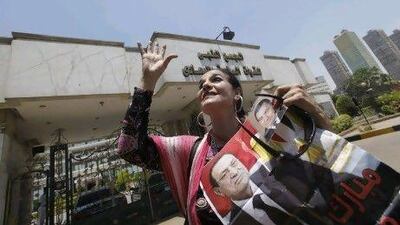 An Egyptian woman chants religious slogans as she holds posters of ousted President Hosni Mubarak outside the Maadi military hospital in Cairo. Mubarak has reportedly suffered a stroke and fallen into a coma.