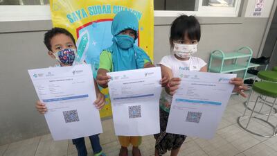 Pupils show their vaccination certificates during an inoculation drive in Jakarta, Indonesia. EPA