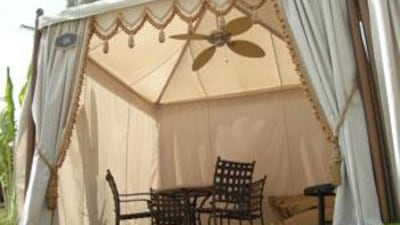 A shady retreat at a Palm Jumeirah home is cooled by the Outdoor Elements fan by The Ceiling Fan Company.