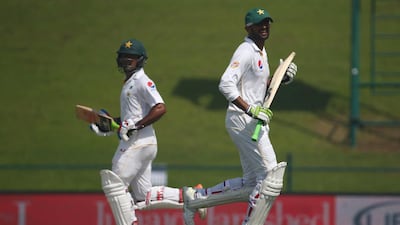 Pakistan's Shoaib Malik, right, and teammate Asad Shafiq run between the wickets during the second day's play of the first Test match against England in Abu Dhabi on October 14, 2015. Marwan Naamani / AFP