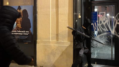 A protester breaks the glass of a bank branch's door during clashes with Catalan regional police forces. AFP
