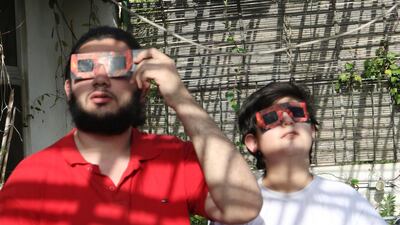 A father and son use special protective glasses to observe a partial solar eclipse from Damascus, Syria. EPA