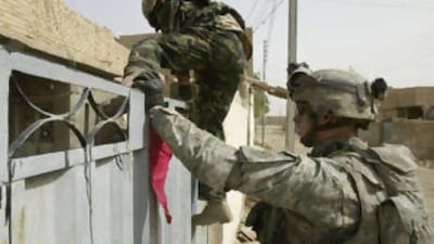 An Iraqi soldier climbs into a house backed-up by a US soldier while conducting a search in a neighbourhood in the north eastern city of Baquba.