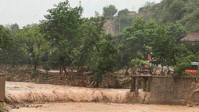 The remainder of a bridge that was washed away by floods along a river in Qingyang, in north-west China's Gansu province, on Saturday. AP