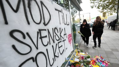 A woman lays flowers in front of a sign which reads 'courage to the Swedish people' near the scene of the fatal shooting in Brussels. AP