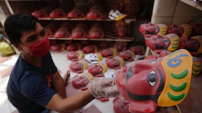 A worker arranges Ondel-ondel masks at a shop in Jakarta. Indonesia has started to loosen Covid-19 restrictions. EPA