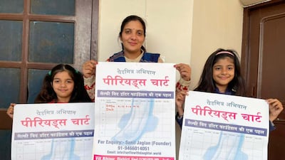 Deepa Dhull posing with her daughters Yachika, 6, and Nandini, 9, holding period charts. Taniya Dutta for The National