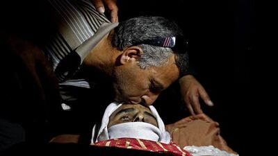 A Palestinian man kisses the forehead of Younis Radaideh during his funeral in the Al Ubiedyeh village near the West Bank city of Bethlehem. Majdi Mohammed / AP Photo