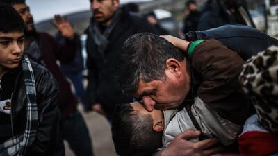 A Syrian father embraces one of his children upon their arrival at the Turkish crossing gate of Cilvegozu from the Syrian city of Idlib on December 17, 2016. Bulent Kilic / AFP