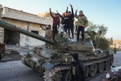 Syrian opposition supporters stand on a captured Syrian army tank in the Maarat Al Numan, southwest of Aleppo, on November 30. AP