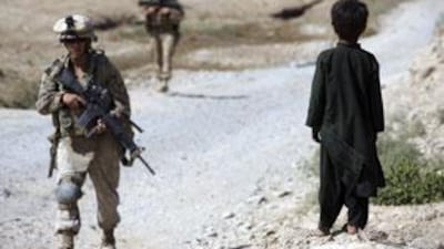 An Afghan boy watches as US marines patrol in Nawa district, Helmand province, southern Afghanistan.