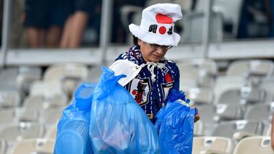 A Japanese fan picks up litter left on the stands at the Mineirao Stadium in Belo Horizonte, Brazil. AFP
