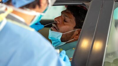 A police officer gets tested at the new screening drive through for COVID-19, Zayed Sports City, Abu Dhabi. Chris Whiteoak / The National