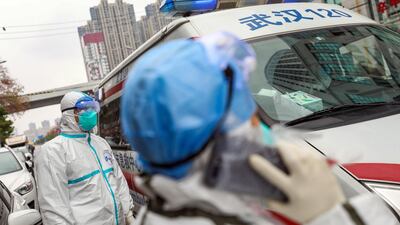 A fully protected ambulance staff waits for his colleague to take an order outside the hospital in Wuhan, Hubei province, Chin. EPA