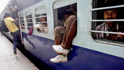 The feet of an Indian man hangs out from an overcrowded train at a railway station in New Delhi. Indian Railways plans to explore low-cost options for raising speeds to between 160kmph and 200 kmph on some routes like Delhi-Agra and Delhi-Chandigarh. Tsering Topgyal / AP Photo