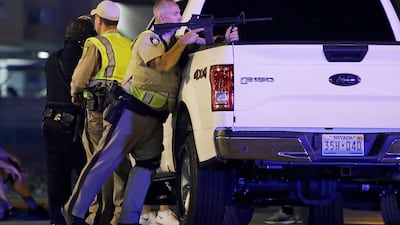 A police officer takes cover behind a truck at the scene of a shooting near the Mandalay Bay resort and casino on the Las Vegas Strip. John Locher / AP Photo